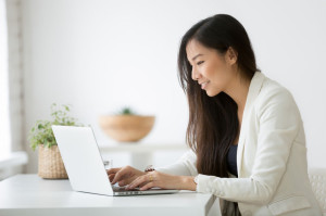Smiling young asian businesswoman using computer working online